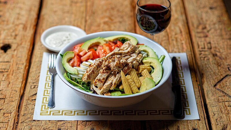 Salad topped with grilled chicken, avocado and corn