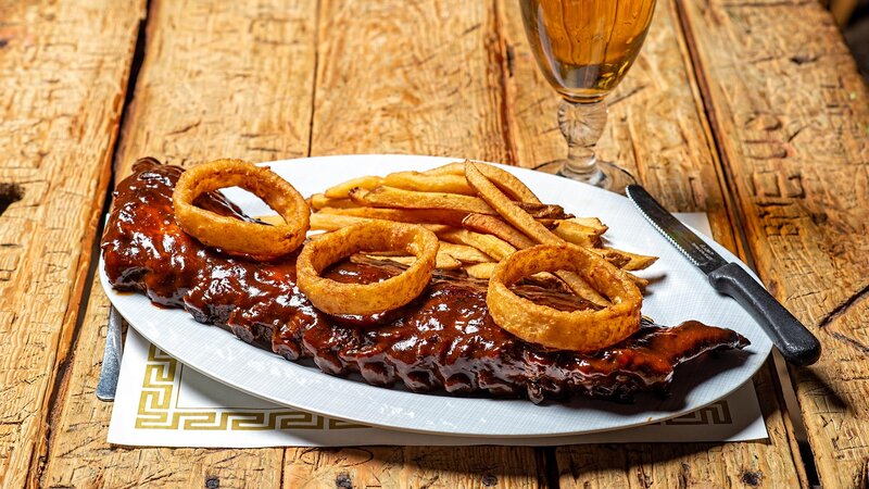 BBQ ribs topped with onion rings and side of french fries